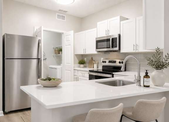 A modern kitchen with a white countertop and stainless steel appliances.