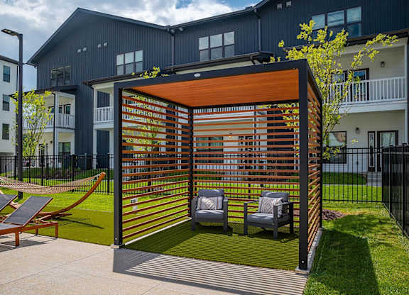 a covered patio with lounge chairs and a hammock