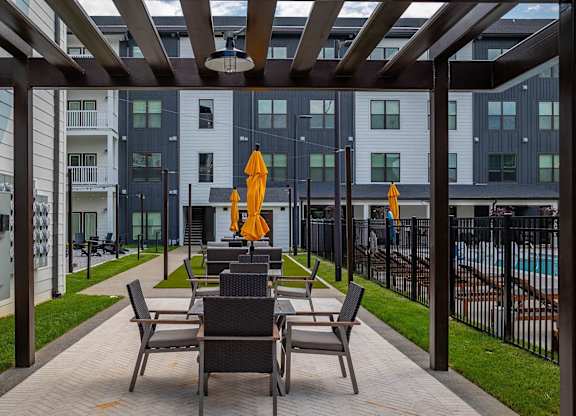 a patio with tables and chairs in front of an apartment building