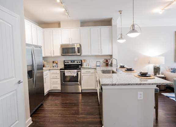 A kitchen with white cabinets and a granite countertop.