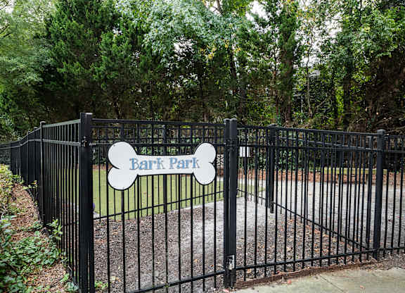 A black fence with a sign that says Bark Park.