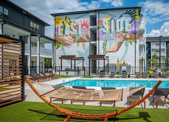 a pool and hammocks in front of a building