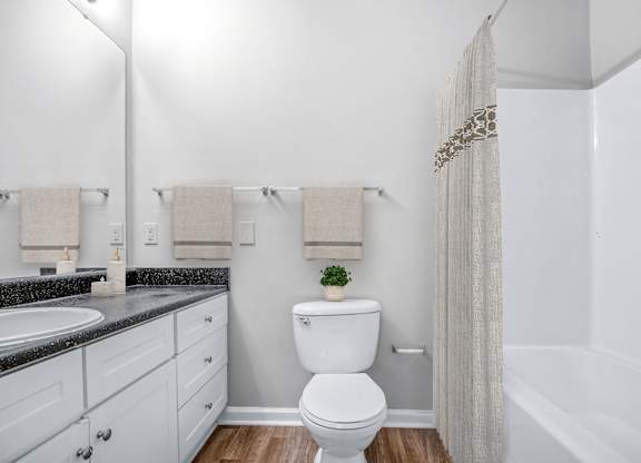 A white toilet in a bathroom with a white shower curtain.