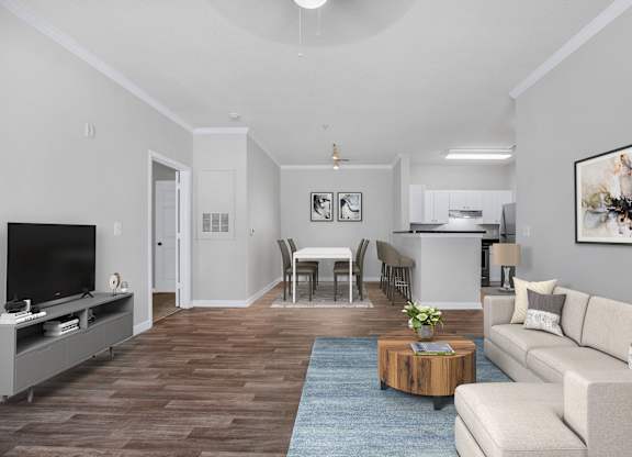 Fairburn, GA, Pet-Friendly Apartments - Orchard Springs Apartment Homes - A Contemporary Open-Concept Living Area Featuring A Cream Sectional, A Round Wood Coffee Table, And A Dedicated Dining Space.