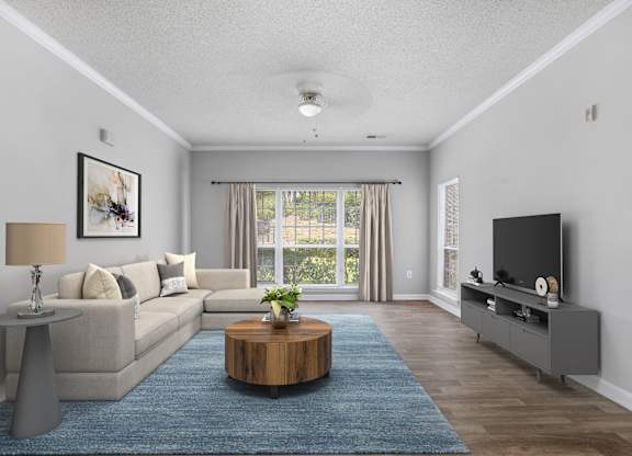 A living room with a grey couch, a wooden coffee table, and a flat screen TV.
