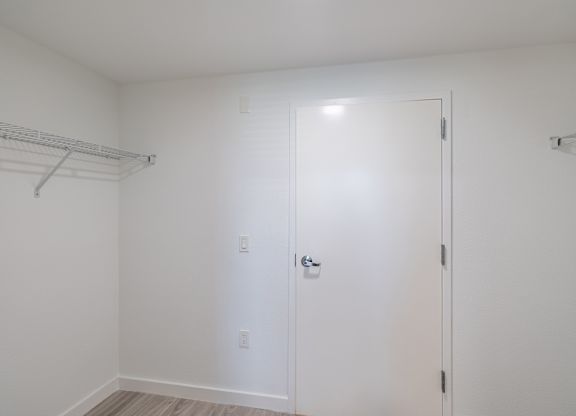 A white closet with a door and a shelf.