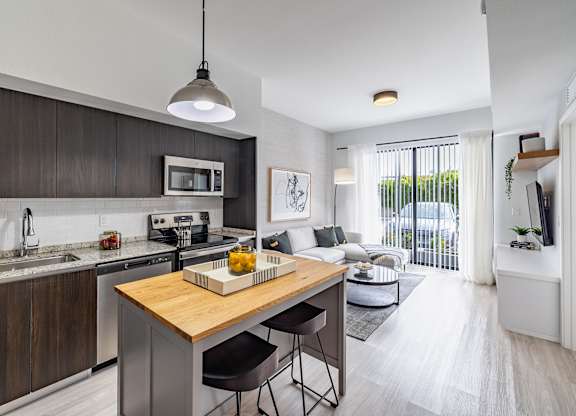 A modern kitchen with a wooden island and stainless steel appliances.
