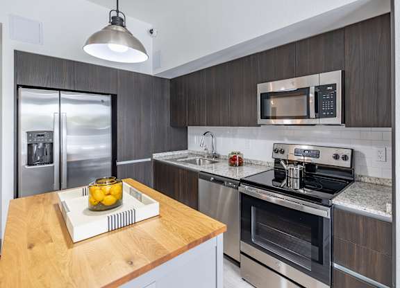 A modern kitchen with a wooden countertop and stainless steel appliances.