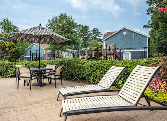 A patio with a table, chairs, and an umbrella.