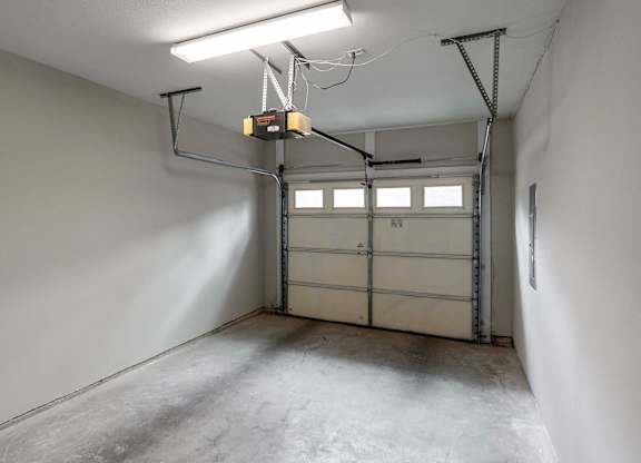 A garage with a white wall and a grey floor.