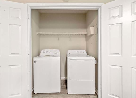 Two white washing machines in a small laundry room.