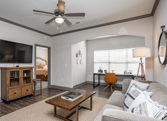 a living room with a ceiling fan and a tv
