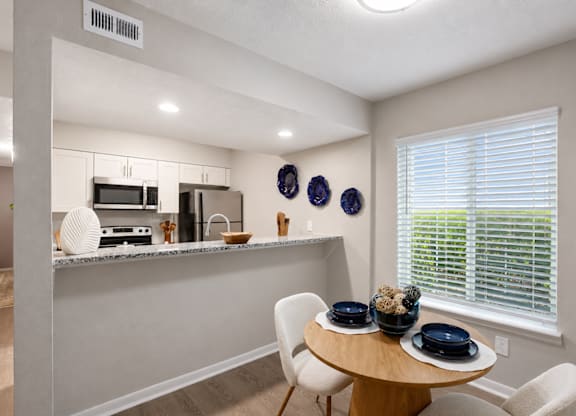 A kitchen with a table and chairs by a window.