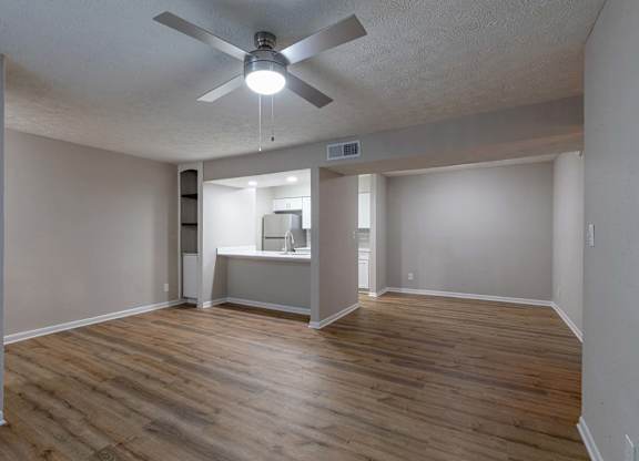 A room with a ceiling fan and wooden flooring.