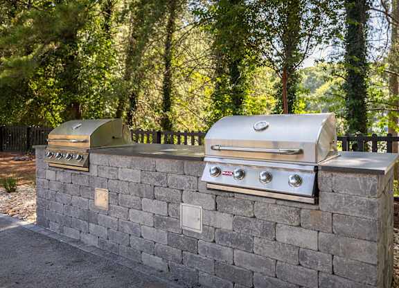 A silver grill is on top of a stone wall.