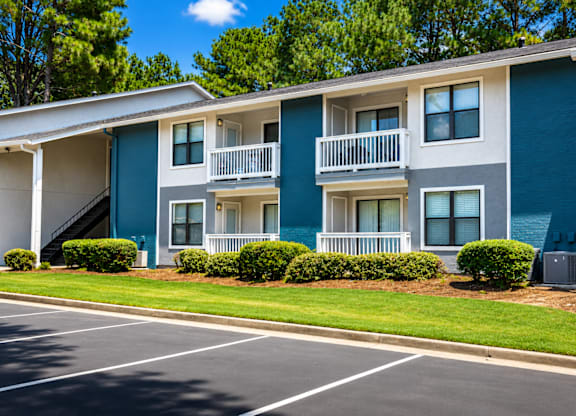 A blue and white apartment building with a parking lot in front.