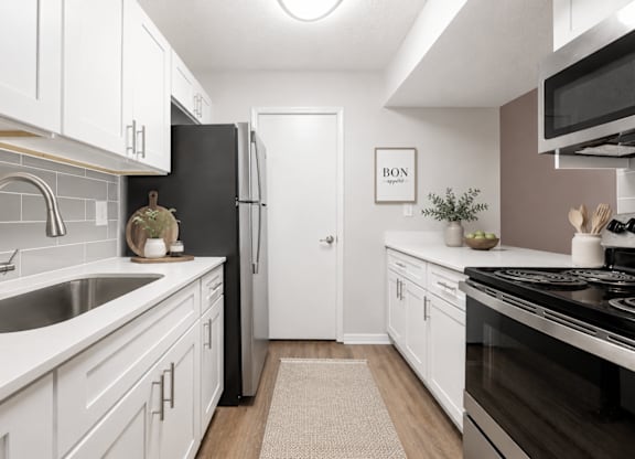 A kitchen with white cabinets and a black refrigerator.