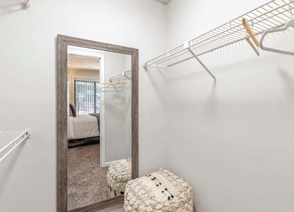 A white closet with a mirror and a shelf.