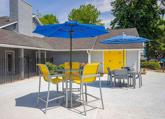A patio with a table and chairs under a blue umbrella.