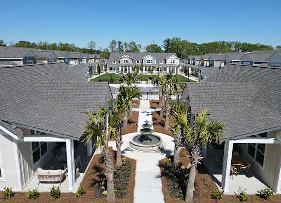 a fountain is in the center of a courtyard with houses at Allier Port Wentworth Apartments, Port Wentworth, GA, 31407