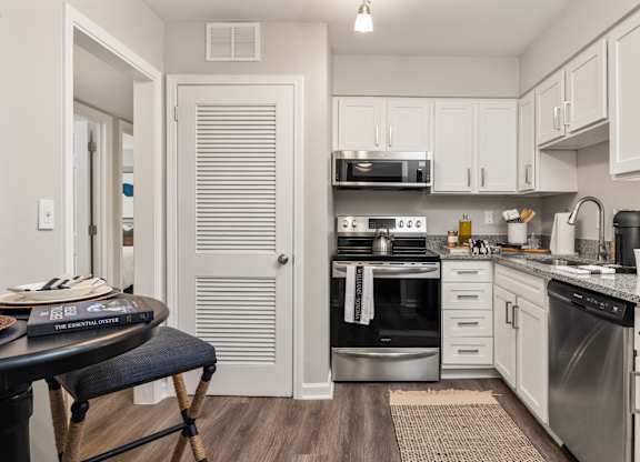 a kitchen with stainless steel appliances and white cabinets at The Brookwood, Alabama, 35209