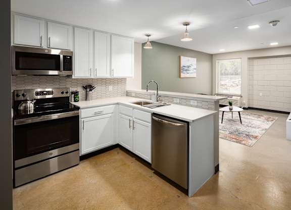 a kitchen with white cabinets and stainless steel appliances at Tower on Tenth Apartments, Birmingham 35205