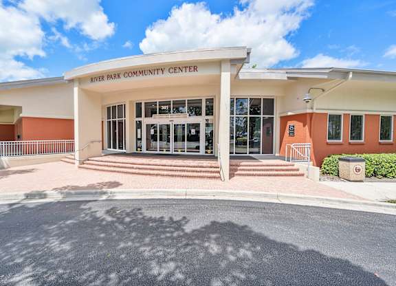 The River Park Community Center is a modern building with a white and orange facade.