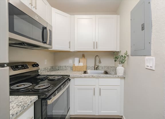 A kitchen with white cabinets and a black stove top oven.