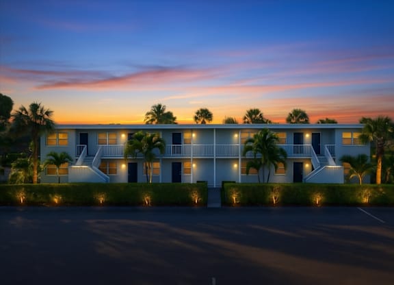 A modern building with a white exterior and palm trees in front.