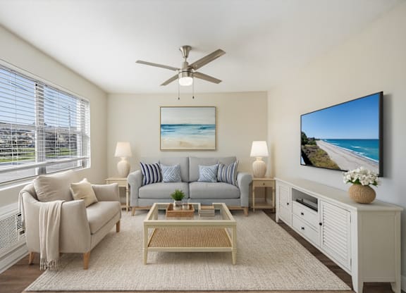 A living room with a grey couch, a coffee table, and a painting of a beach scene on the wall.