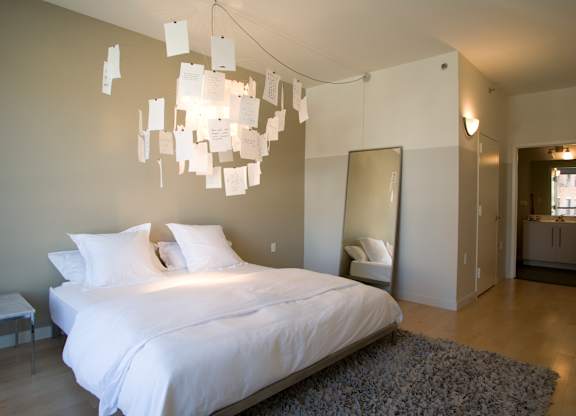 A bedroom with a bed, a mirror, and a chandelier.