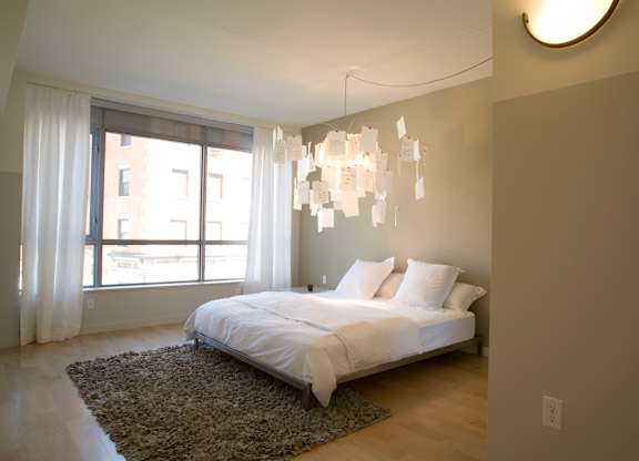 A bedroom with a large bed and a chandelier.