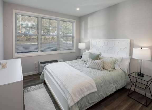A bedroom with a large bed and a window with blinds.