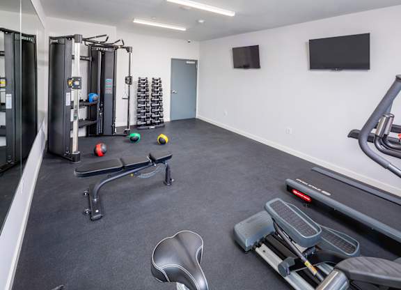 A gym with a variety of equipment including a treadmill, weights, and a bench press.