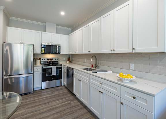 A modern kitchen with white cabinets and a stainless steel refrigerator.at Station Village at Denville, Denville, NJ 07834