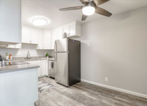 an empty kitchen with a refrigerator and a ceiling fan