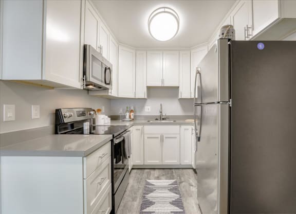 a white kitchen with stainless steel appliances and white cabinets