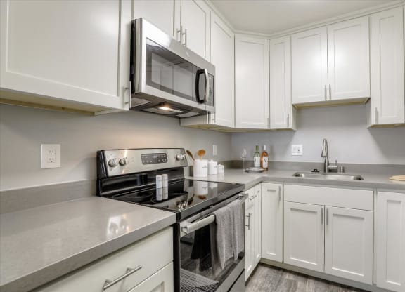 a white kitchen with stainless steel appliances and white cabinets