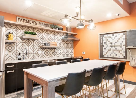a kitchen with a large white table and black and white tiles on the wall