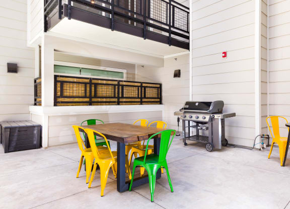 a patio with a table and chairs and a grill