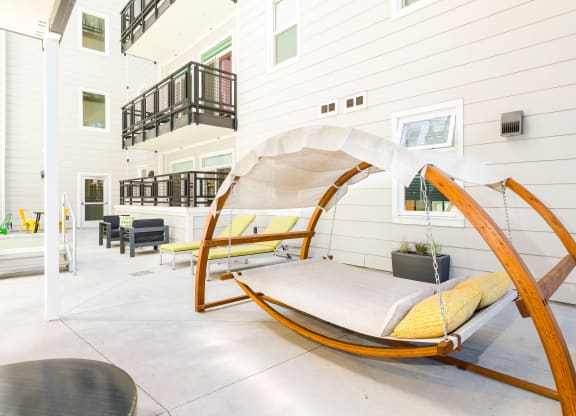 a porch swing with yellow pillows and a gray blanket