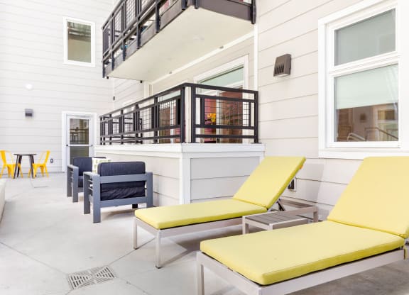 a patio with yellow lounge chairs and blue and yellow chairs
