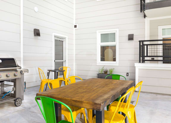 a patio with a table and chairs and a grill