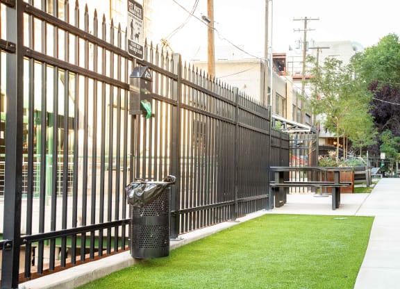 a fence with a bench and trash can in front of it