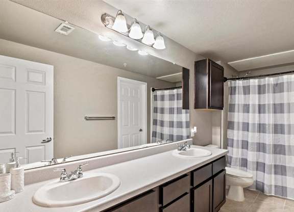A bathroom with a sink, mirror, and shower curtain.