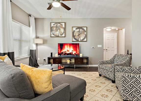 A living room with a grey couch, a fireplace, and a ceiling fan.
