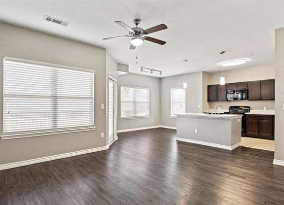 A spacious room with a ceiling fan and wooden flooring.