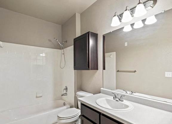 A white bathroom with a white toilet, sink, and a mirror.