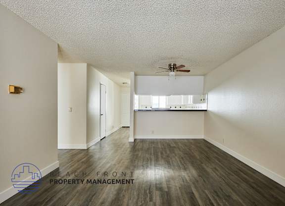 A spacious room with a ceiling fan and a logo for Beach Front Property Management.