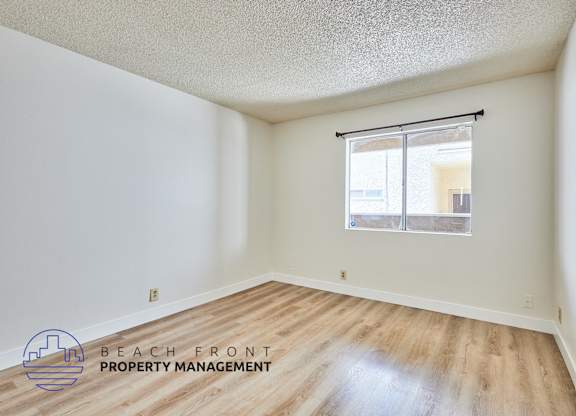 A room with wooden floors and a window with blinds.